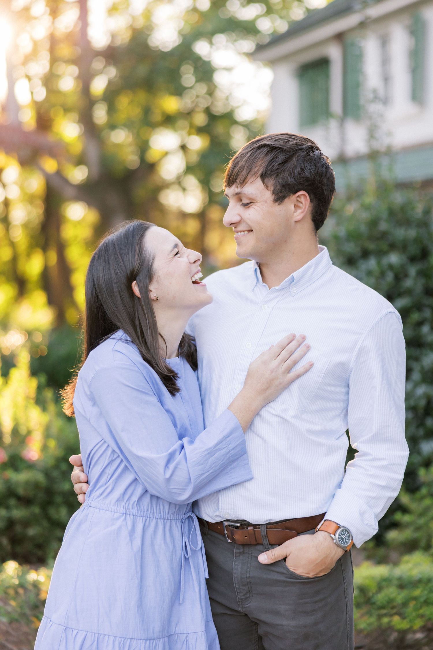 A romantic couple in coordinated blue and white outfits share a joyful moment in a sunlit garden setting.