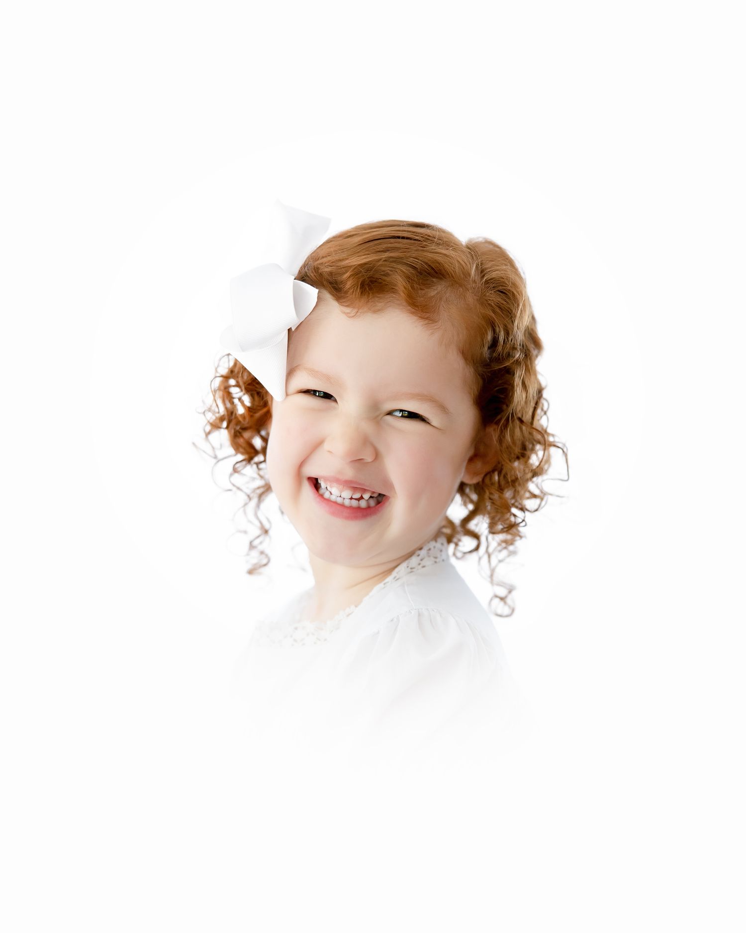 Studio portrait showing delightful expression with curly reddish hair wearing white against bright background.