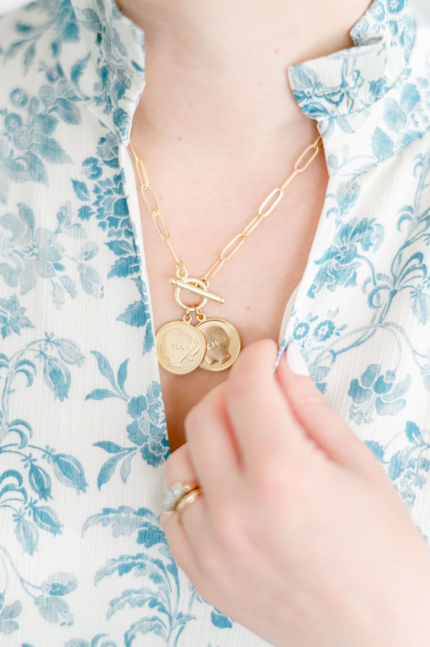 Close-up of gold chain necklace with pendant against floral print fabric.
