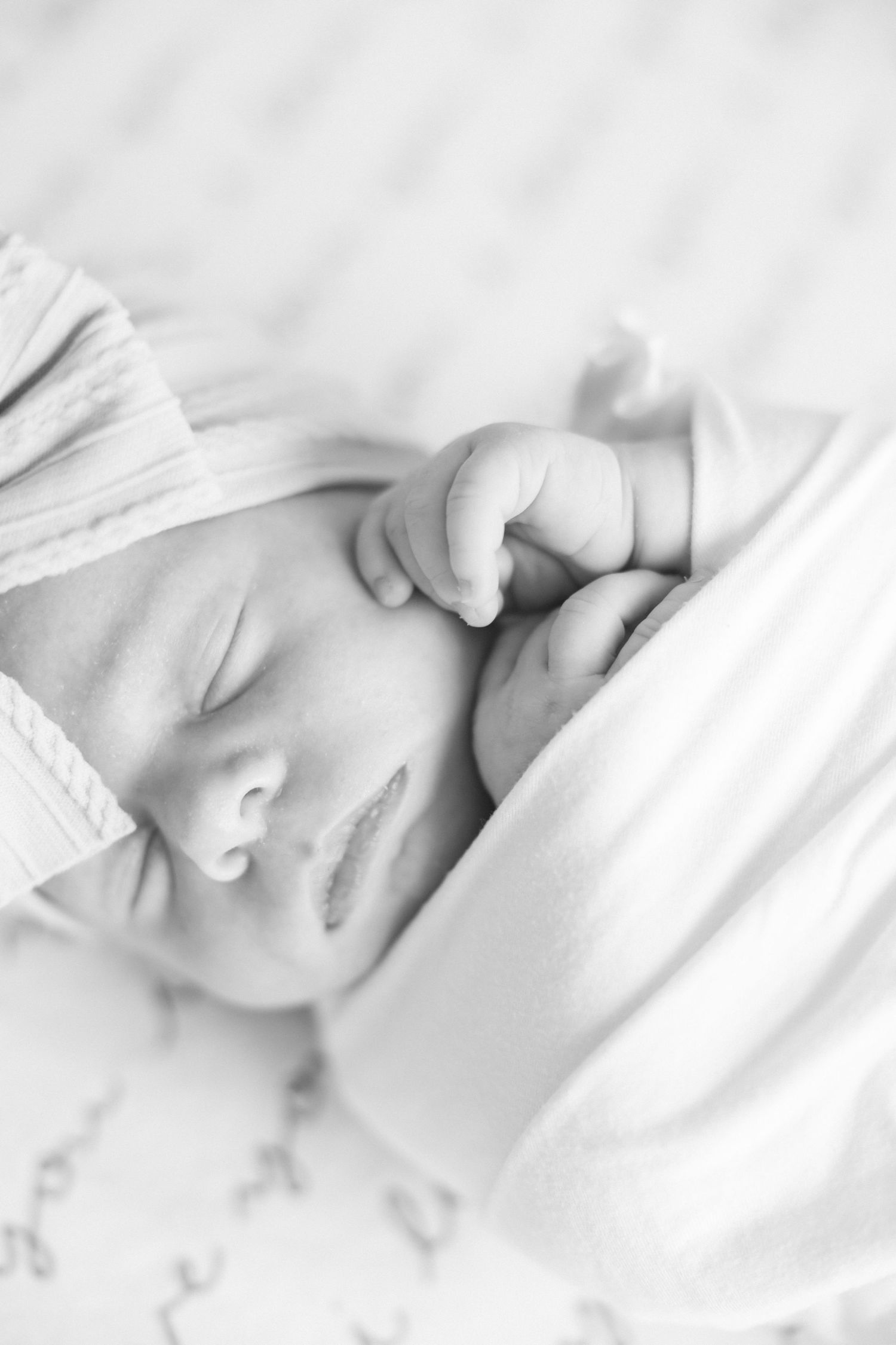 A peaceful sleeping newborn baby swaddled in soft white bedding.