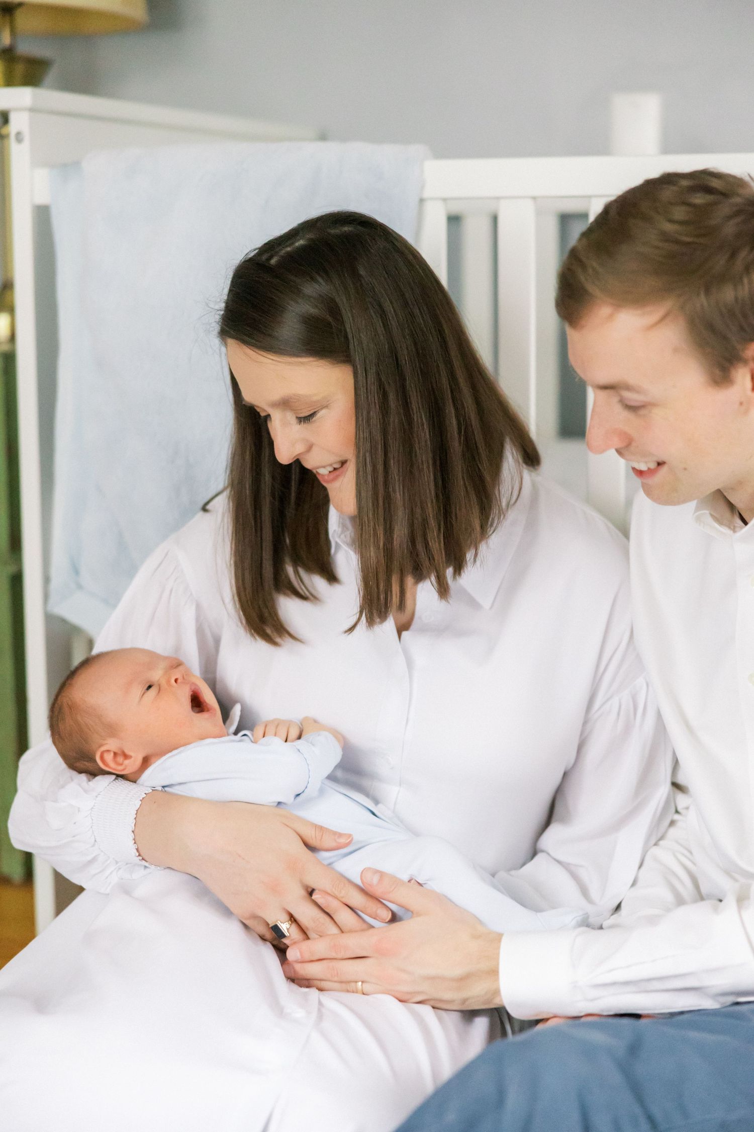 Parents share an intimate moment with their newborn baby in a nursery setting.