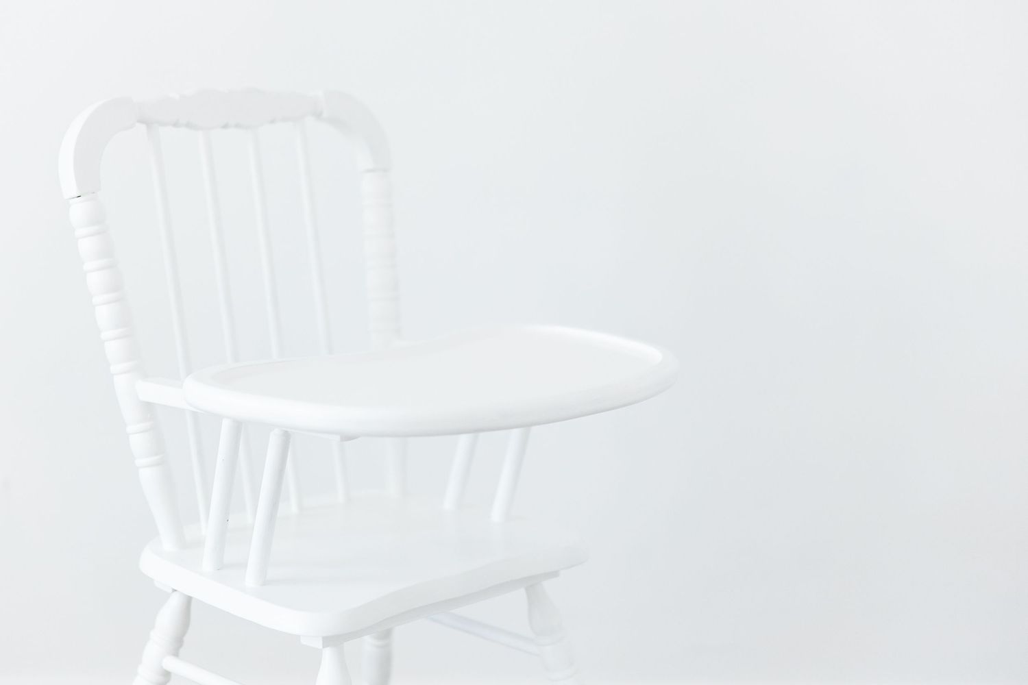 White vintage rocking chair with spindle back against white background creates a minimalist monochromatic look.