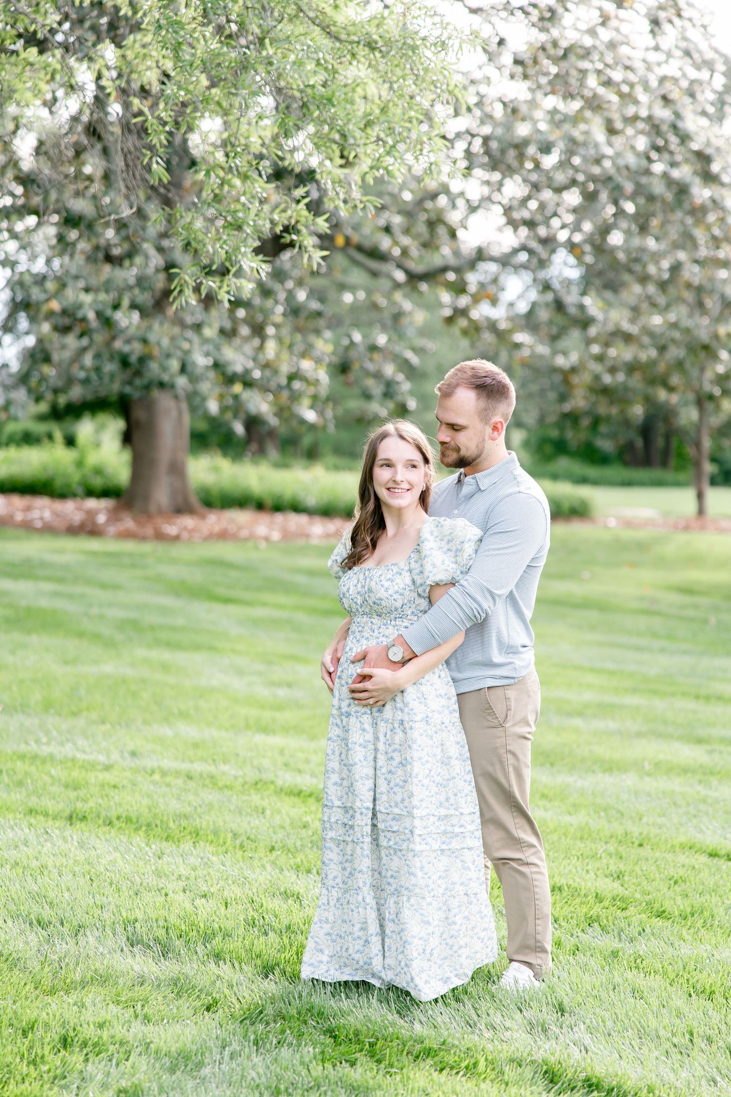 A couple embraces in a blooming spring garden as flowering trees create a romantic backdrop on a sunny day.