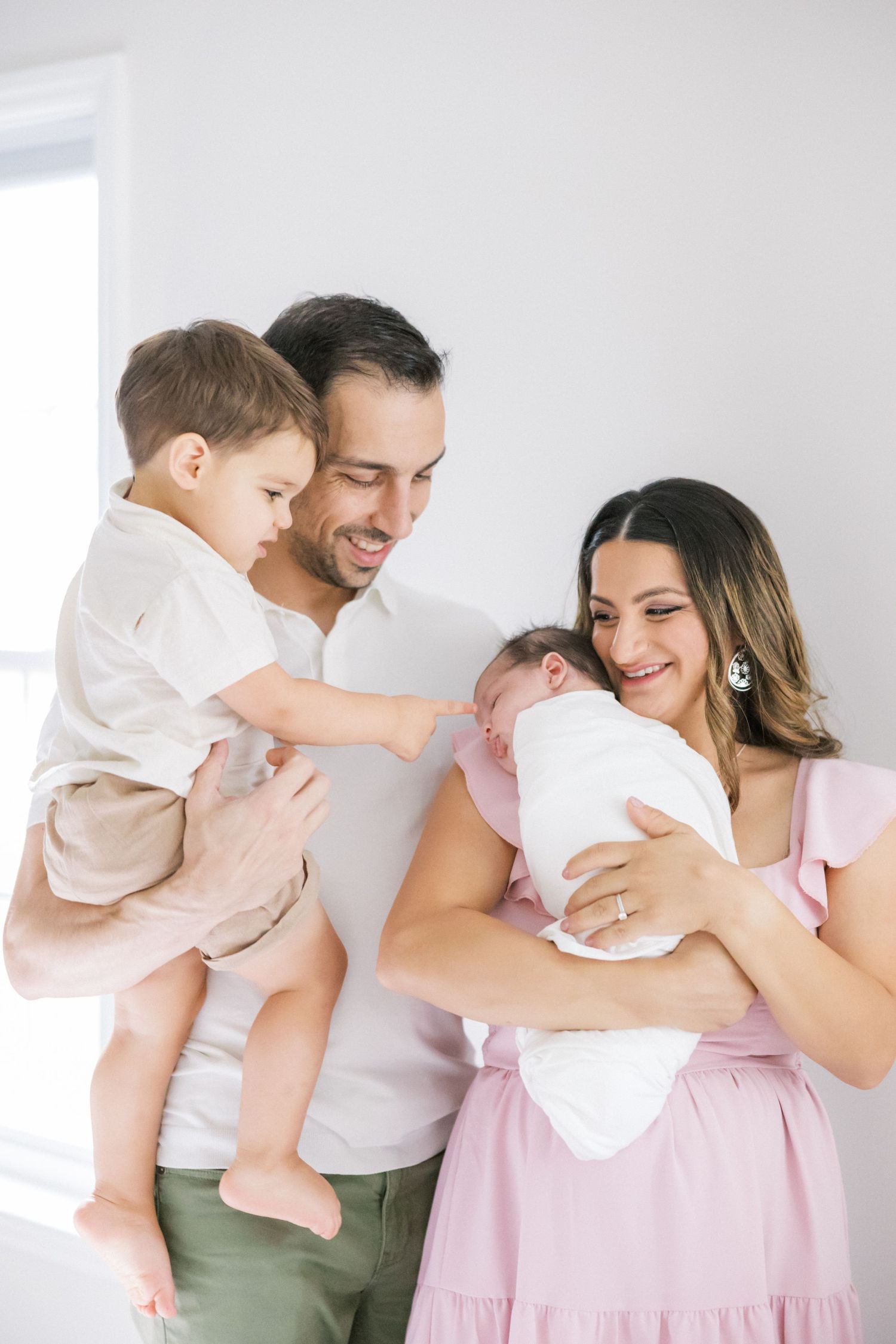A family sharing a tender moment together indoors with their newborn baby.