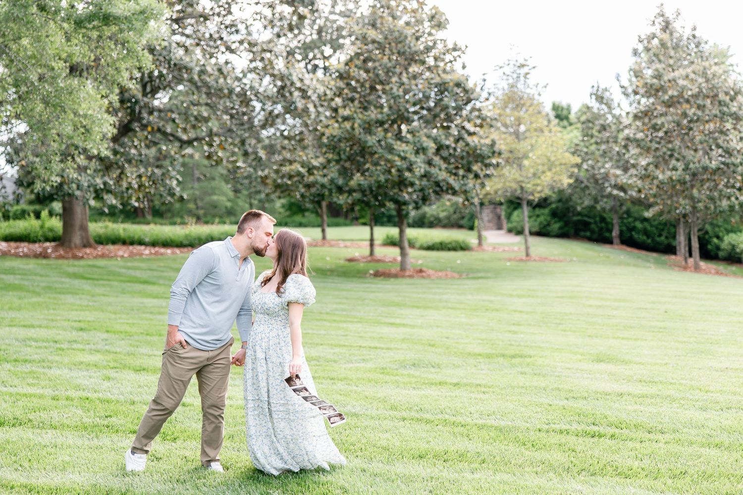 A tender moment shared in an orchard garden with flowering trees and manicured green lawns.