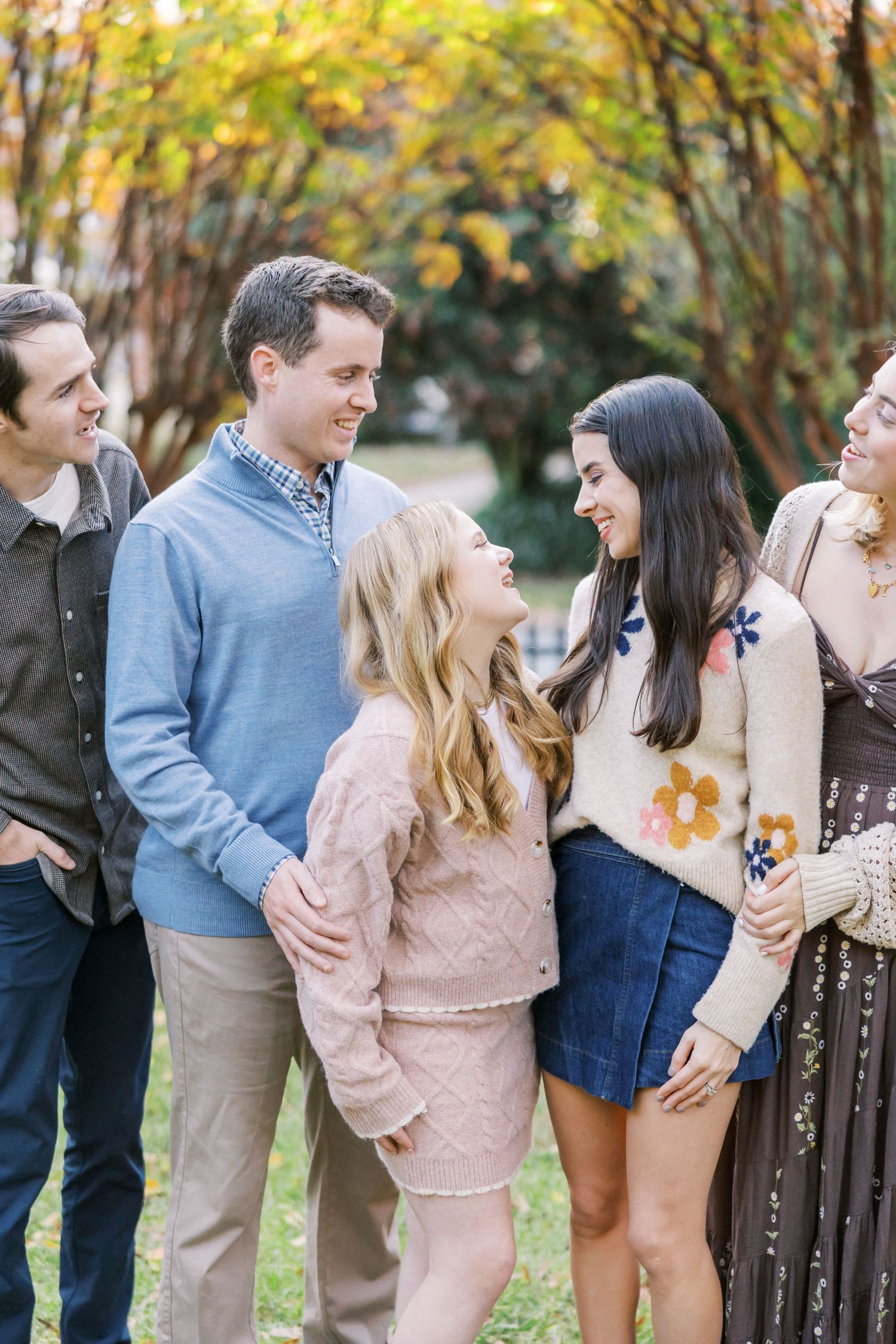 Small group having a candid moment together outdoors with fall trees in the background.