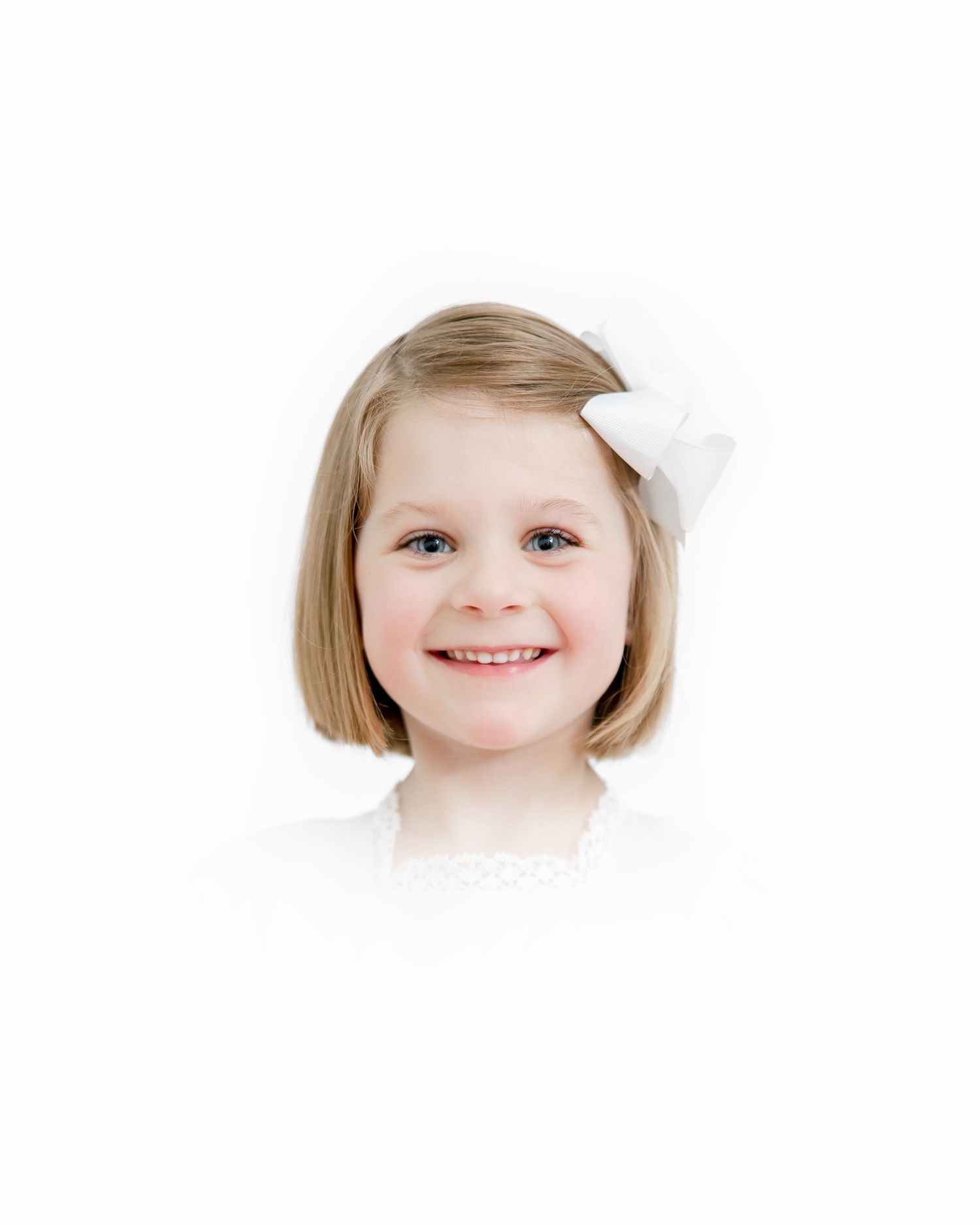 Portrait of a young child with a short blonde bob haircut and white bow smiling warmly against a white background.
