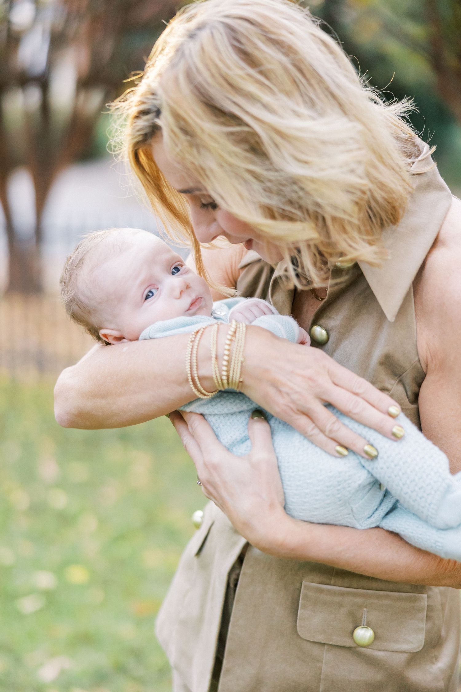 A tender moment between parent and infant baby outdoors in an autumn setting.