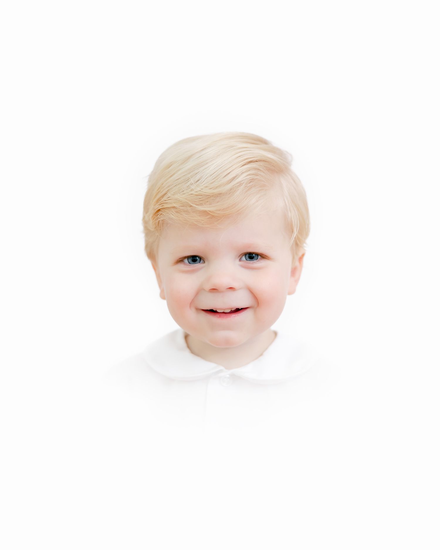 Portrait of a smiling young child with light blonde hair and a white collar against a plain white background.