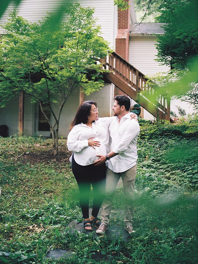 A couple shares an intimate moment together in a lush green garden setting with stairs in the background.
