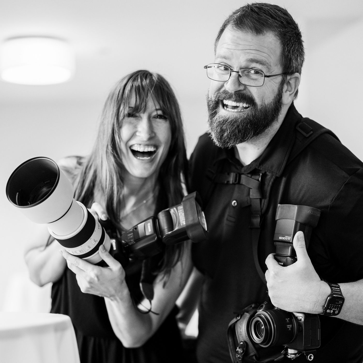 Two photographers pose with their professional cameras in a series of candid black and white shots.