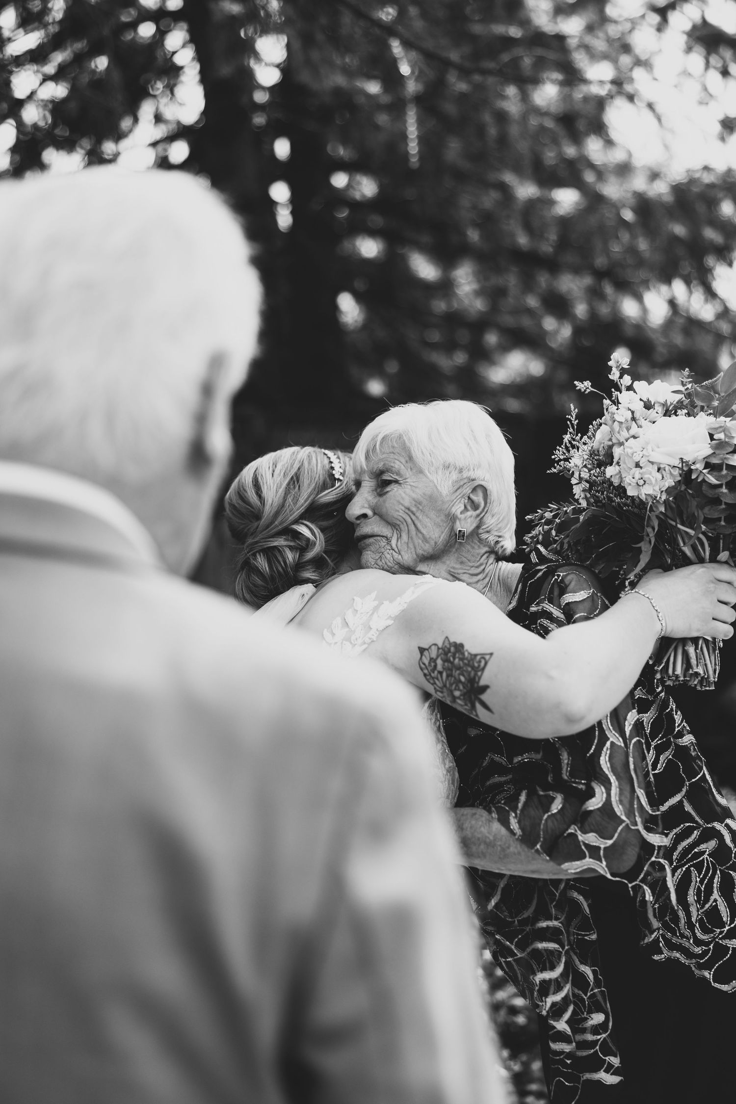 A soft black and white floral wedding scene showing elegant white blooms and greenery in an outdoor setting.