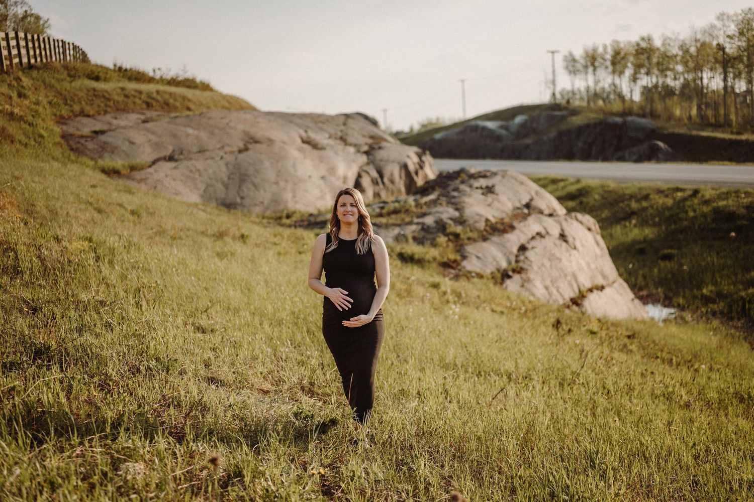 A couple walks together through green rolling hills and rocky terrain during an outdoor engagement photoshoot session.