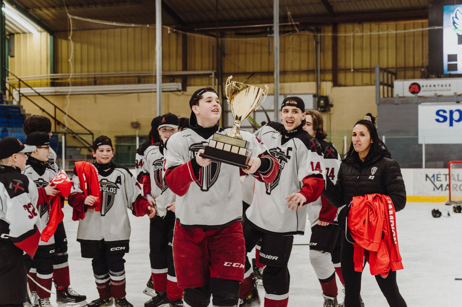Ice hockey teammates celebrate together along the boards after scoring during a game.