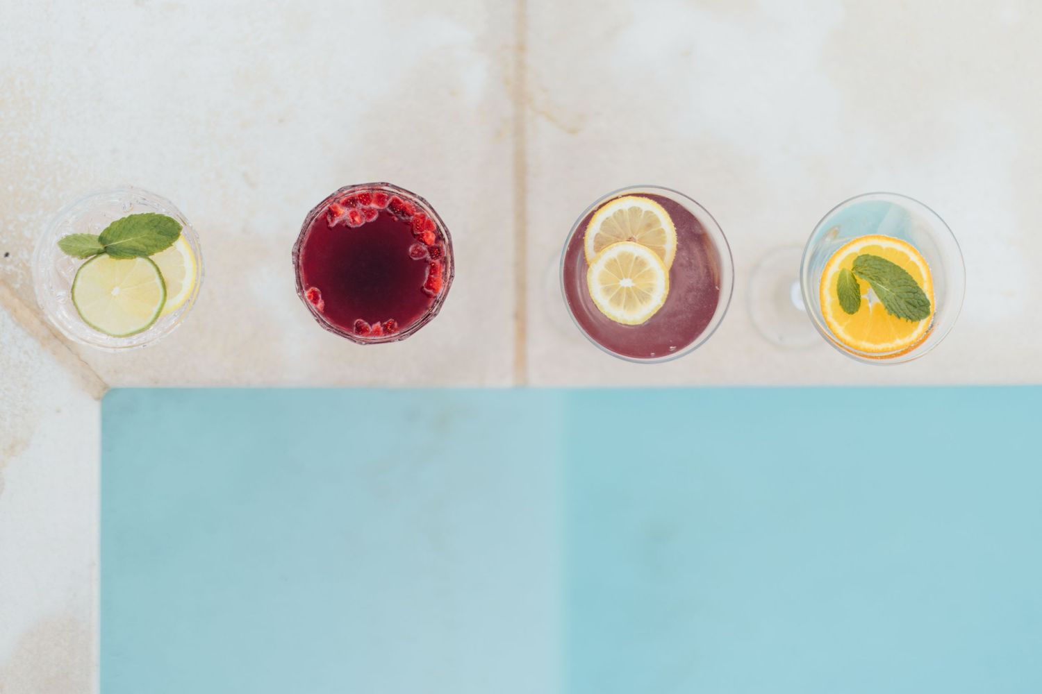 Fresh citrus drink with lemon and berry garnishes served in a glass with ice cubes on a light surface.