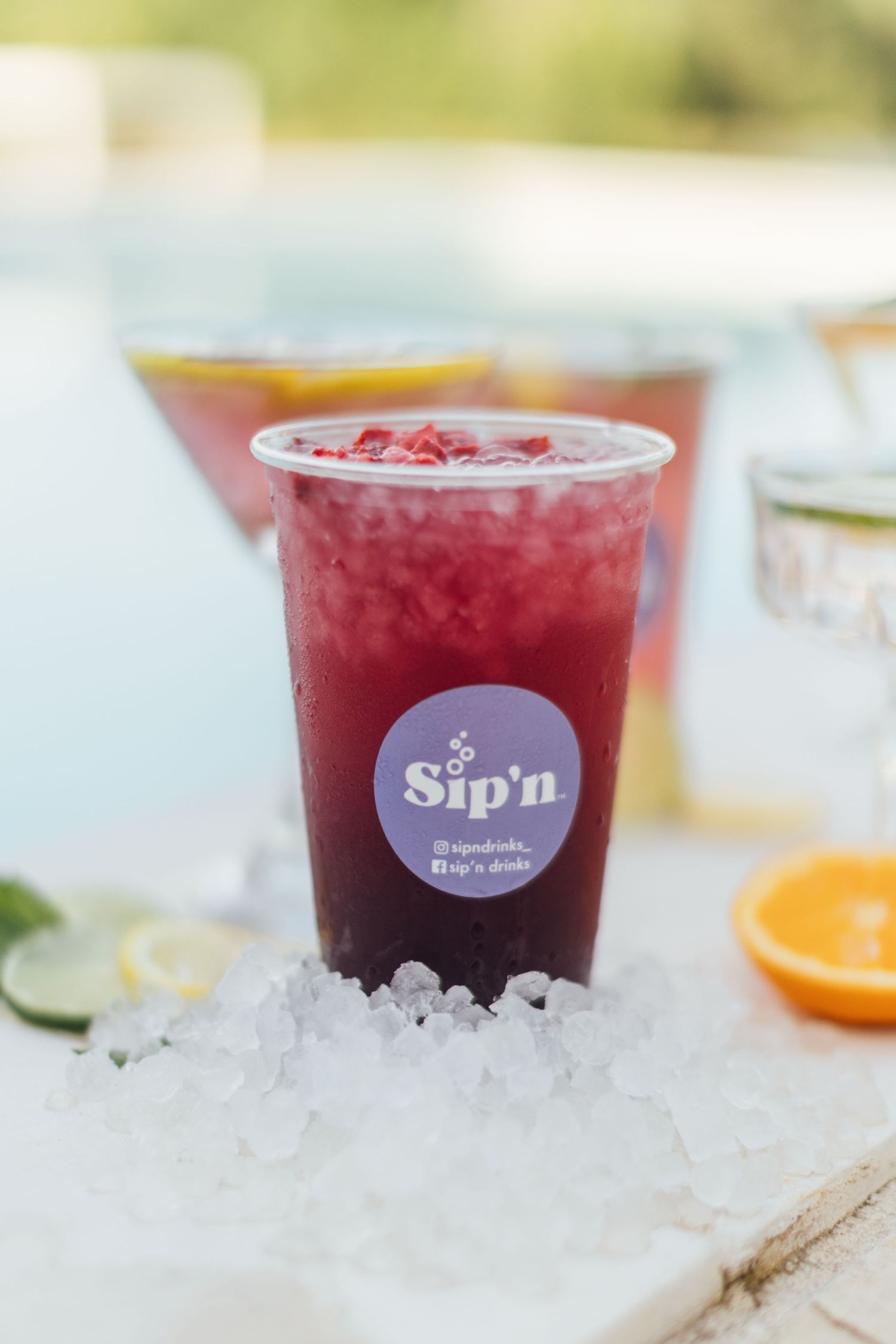 A refreshing red berry drink served in clear cups with crushed ice and the Sip'n logo visible on the side.