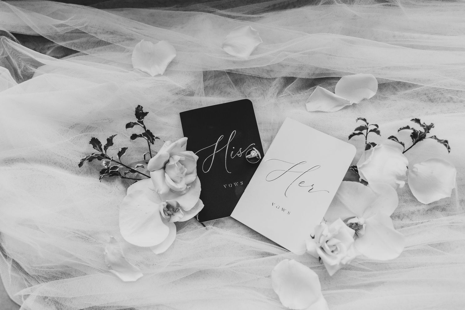 Wedding vow books with white flowers and delicate tulle fabric.