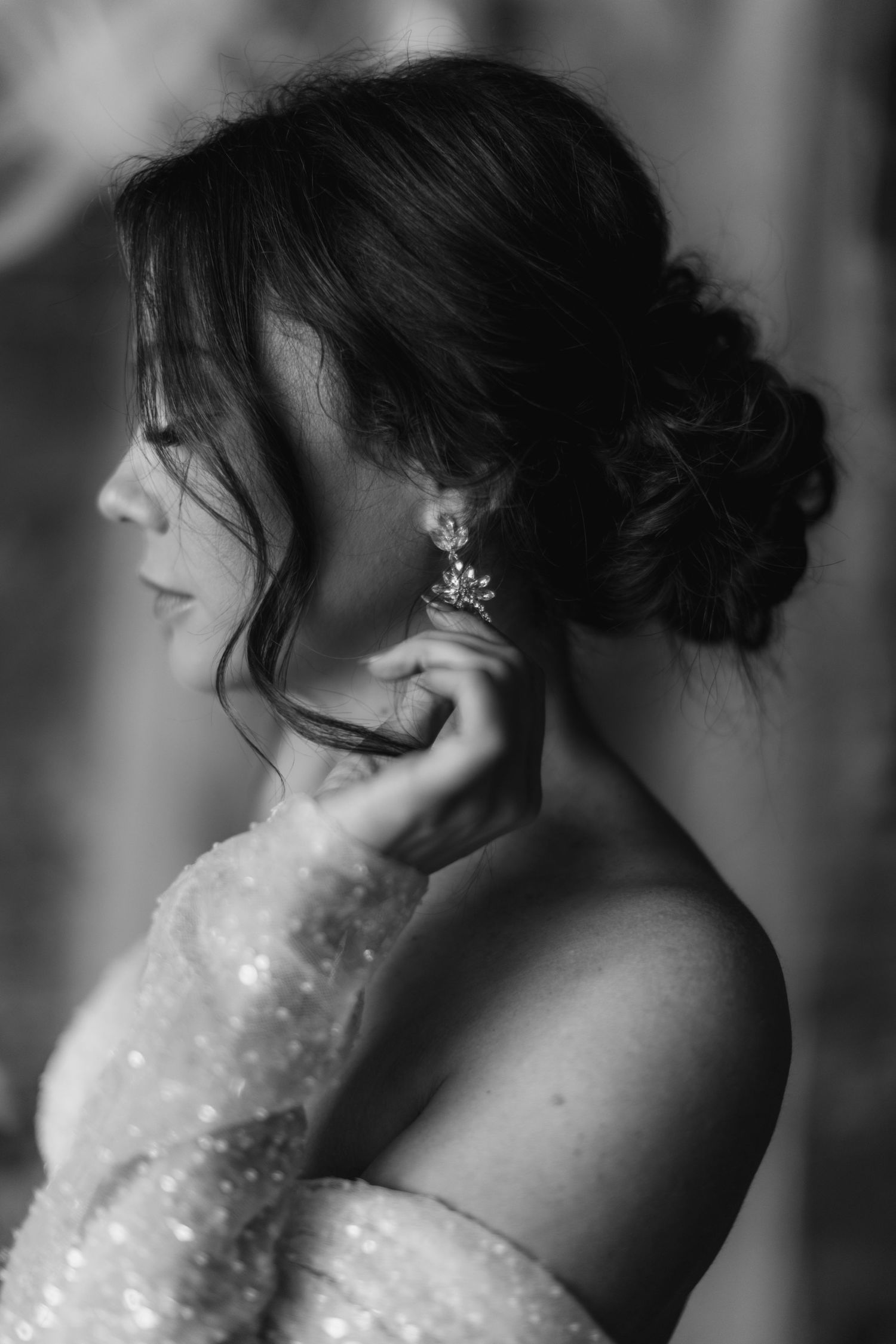 Close-up black and white portrait showing sparkly dress details and an elegant updo hairstyle with hair accessories.