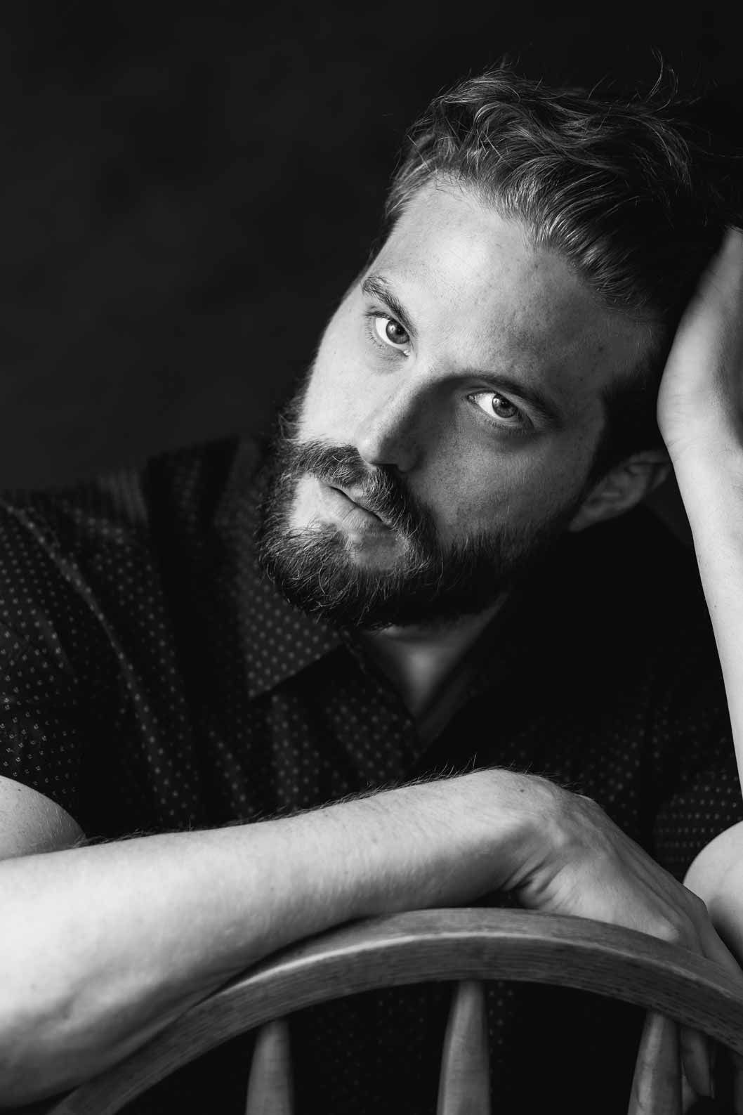 Creative male portrait photography in black and white with dramatic studio lighting and pose