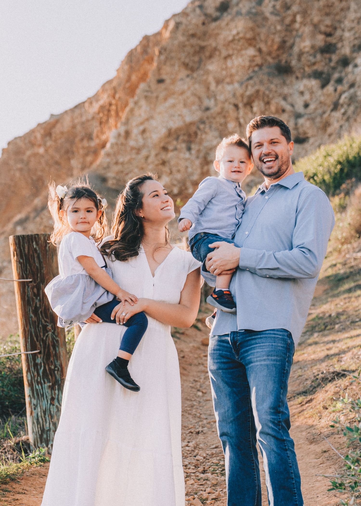 Family enjoying a tender moment together outdoors on a mountain trail during golden hour.