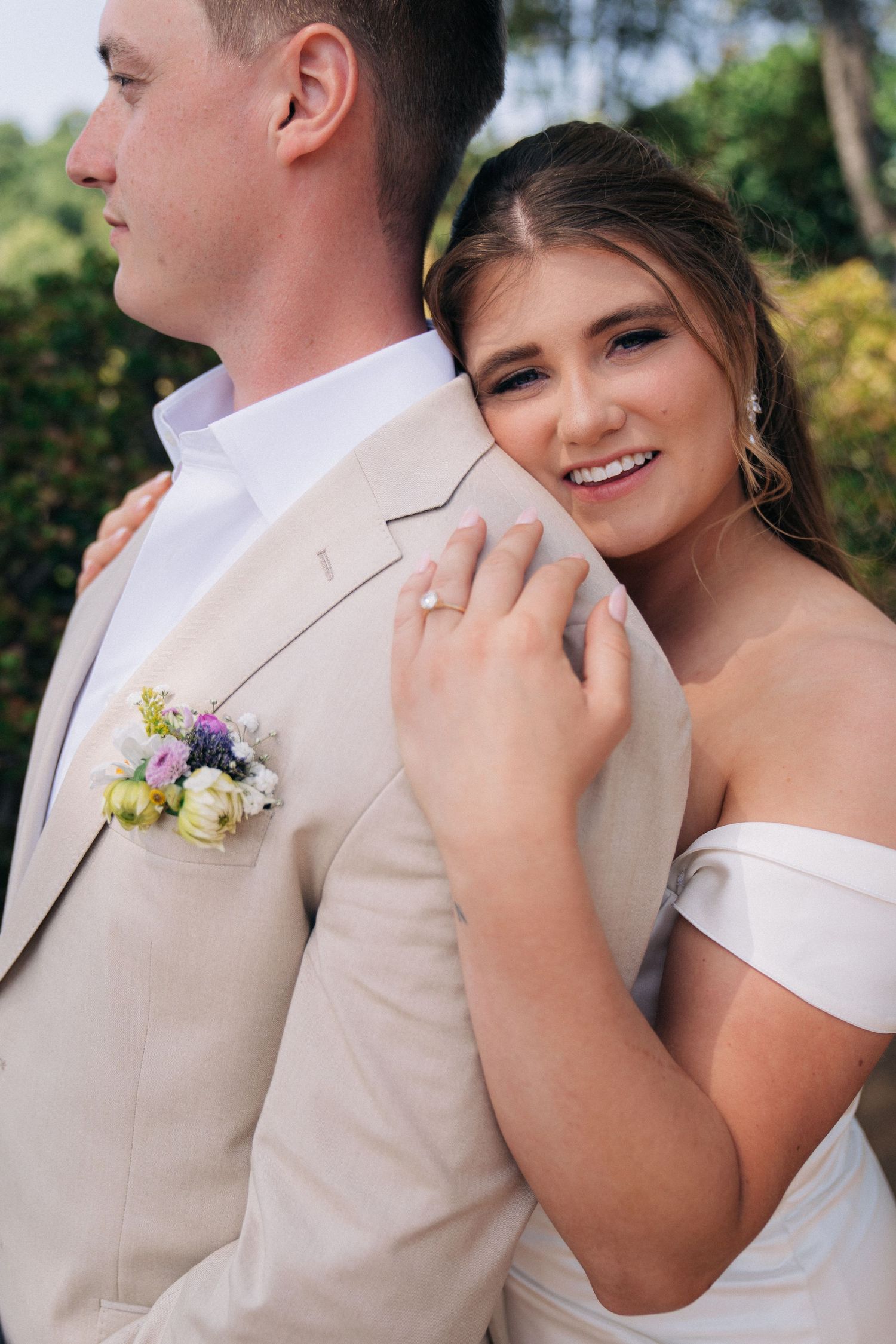 A romantic couples photo series in a garden setting with coordinating beige and white wedding attire and floral accents.