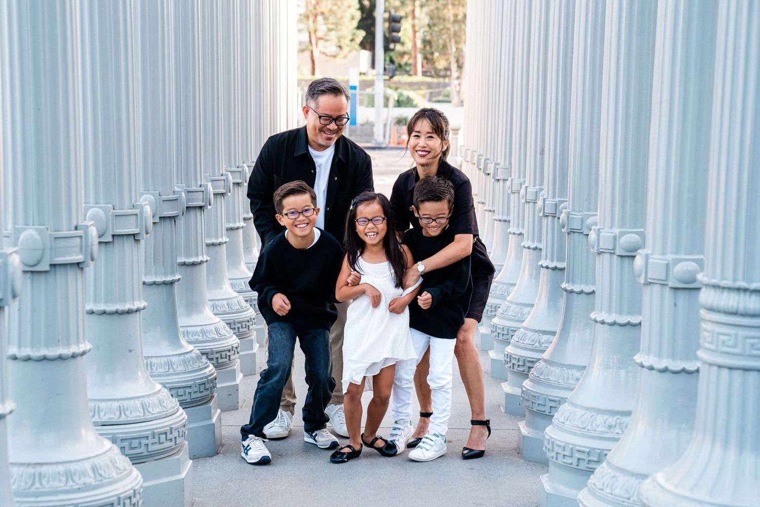 Group of people interact and pose among tall illuminated white columns at the Urban Light art installation in Los Angeles.