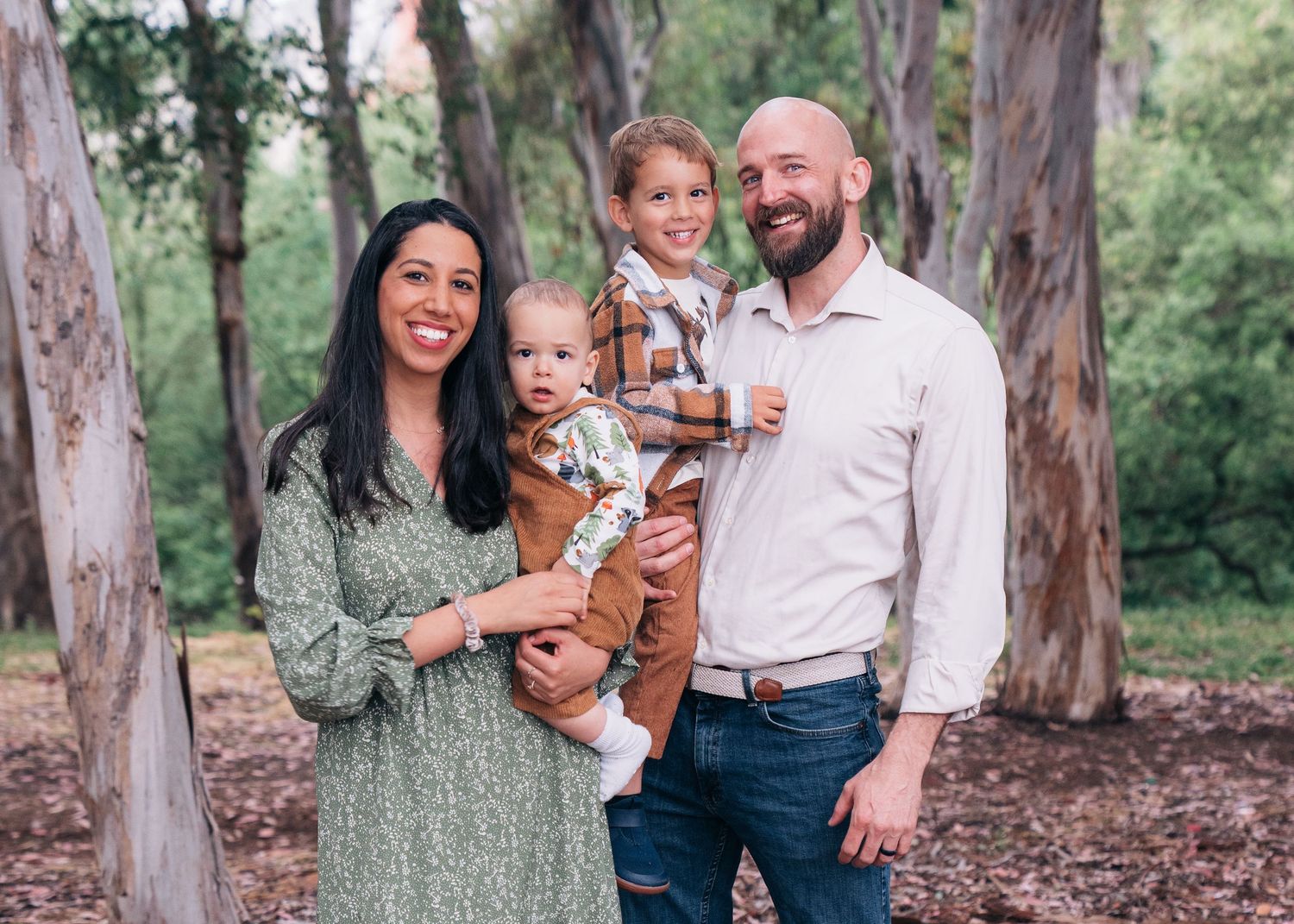 Family enjoying a casual outdoor portrait session in a eucalyptus grove with natural lighting.