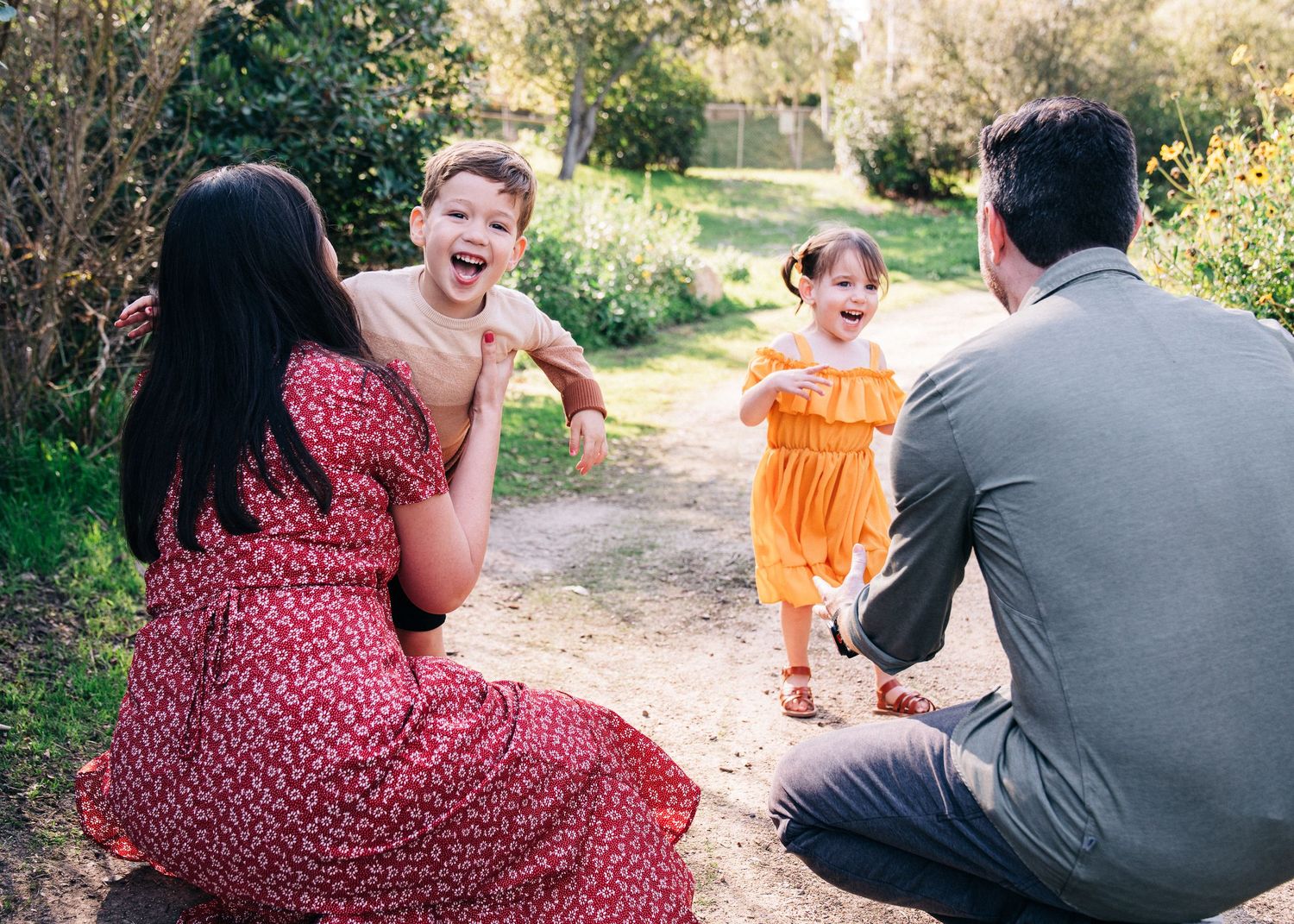 A couple spends time together outdoors on a sunny path surrounded by greenery and trees.