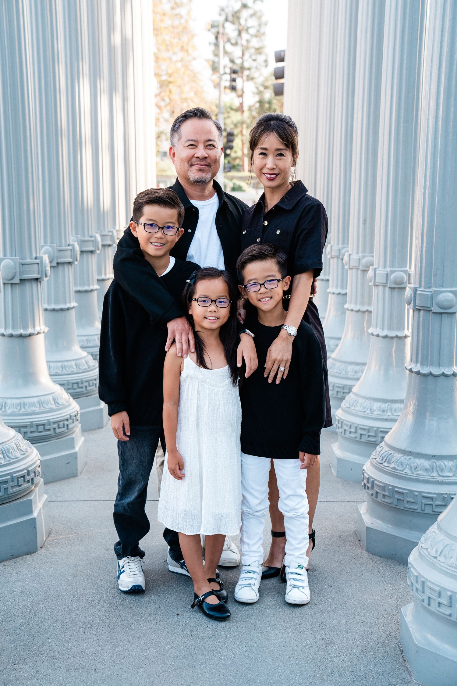 Family poses together among white urban light posts at LACMA's iconic outdoor installation during daytime.