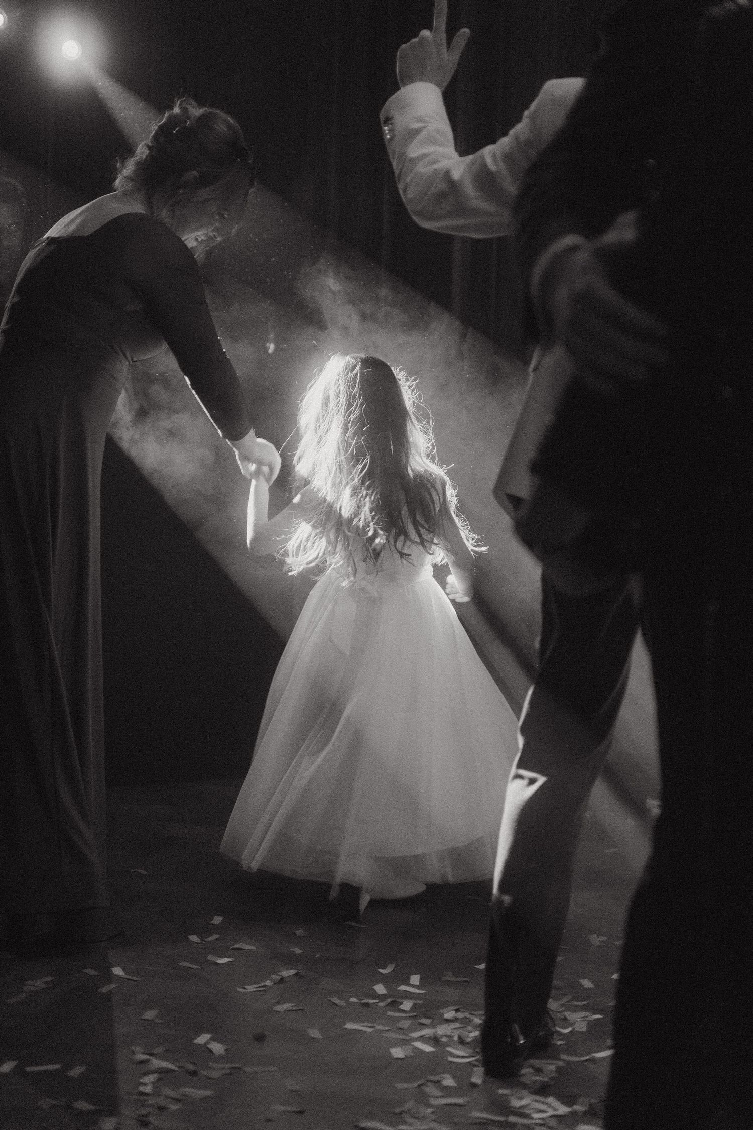 A backlit figure in a flowing white dress performs on a misty stage with theatrical lighting creating a dramatic atmosphere.