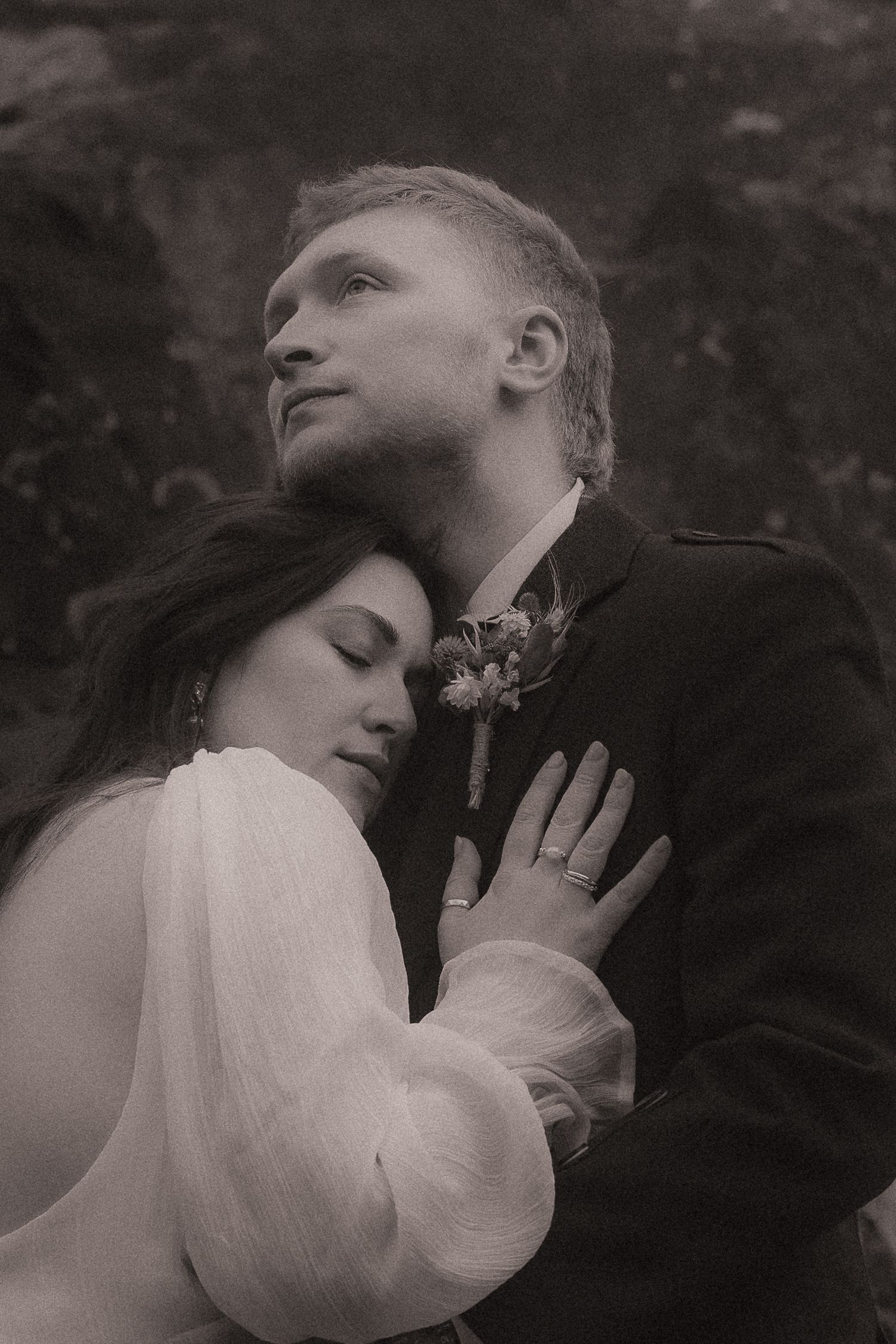 Romantic black and white wedding portrait showing intimate embrace between couple with vintage soft focus effect.