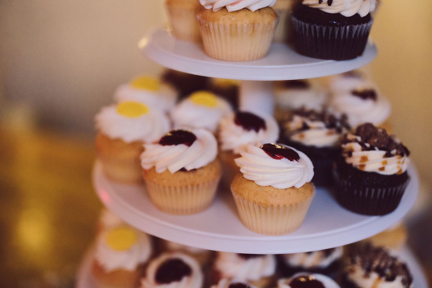 a tiered tray of cupcakes with white frosting.