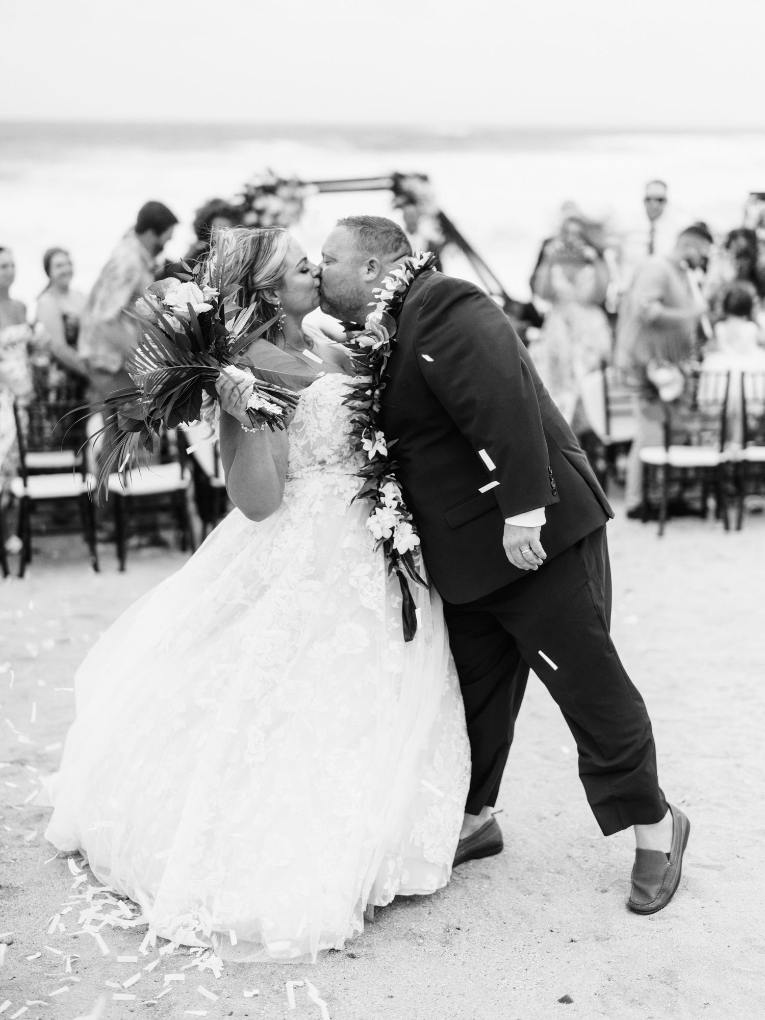 Black and white wedding photos showing playful moments between newlyweds on the beach.