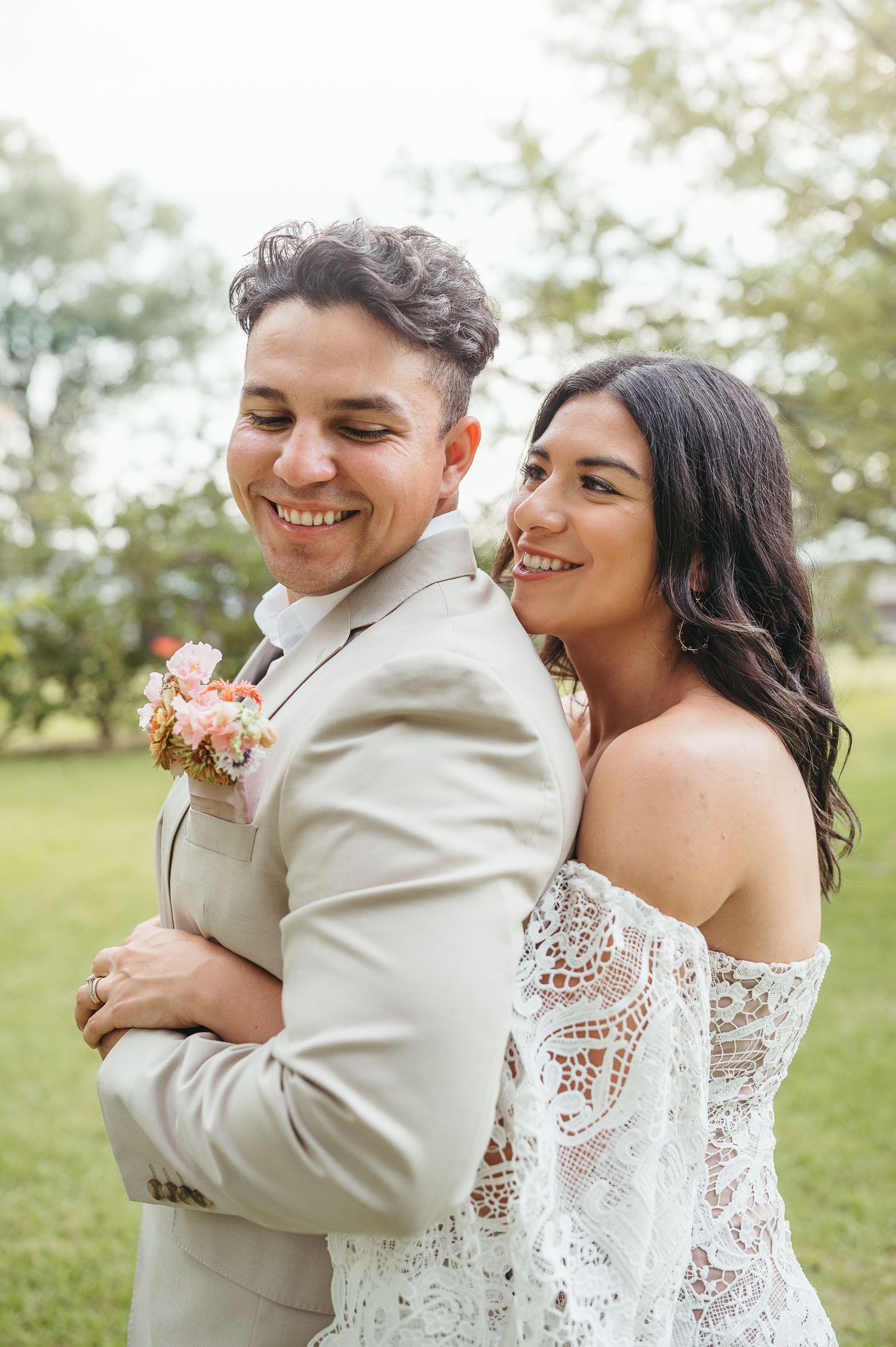 Candid portrait of happy wedding couple sharing a laugh in outdoor garden setting.