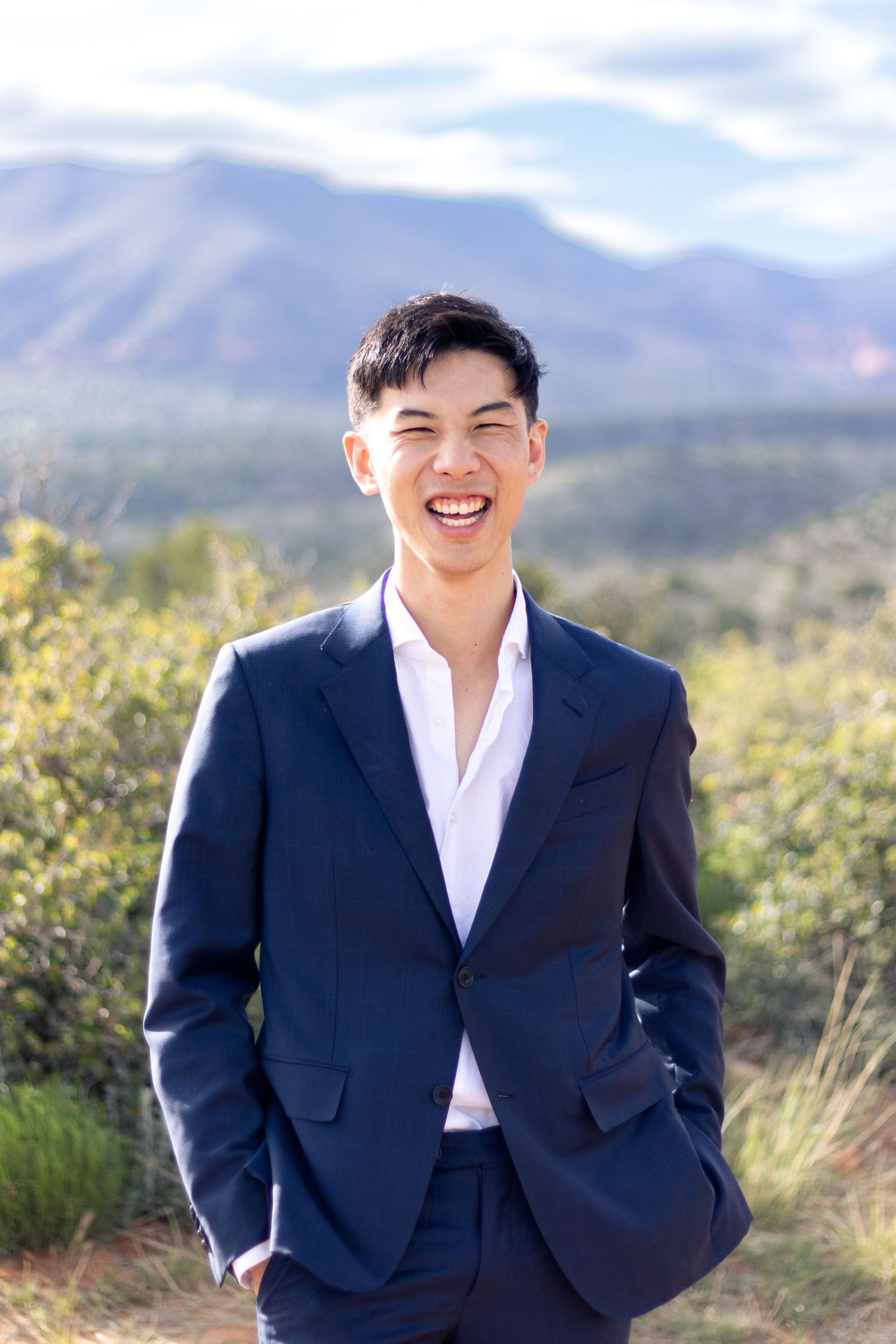 Professional portrait against mountain backdrop wearing navy suit and white dress shirt.