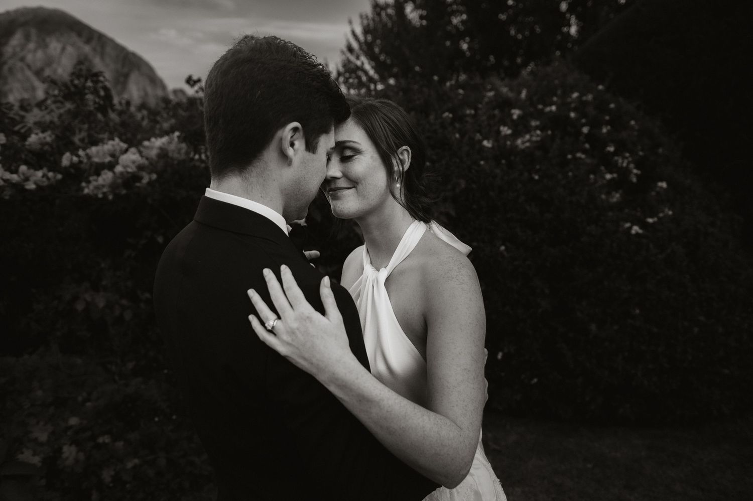 Intimate black and white portrait of a couple sharing a romantic moment outdoors.