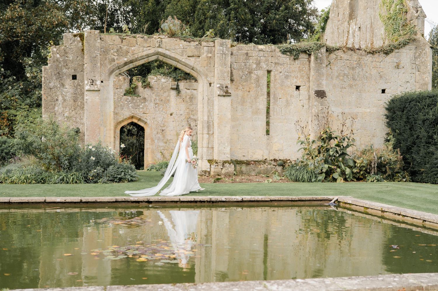 Elegant bridal portraits captured in front of ancient stone ruins with a reflecting pool.