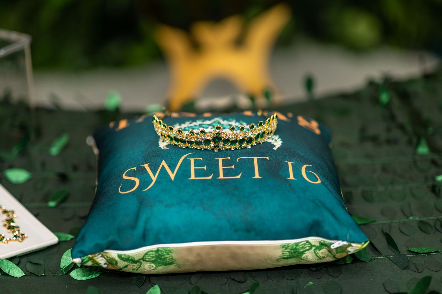 Elegant table settings featuring emerald green and gold decor with crowns and a sweet sixteen theme.