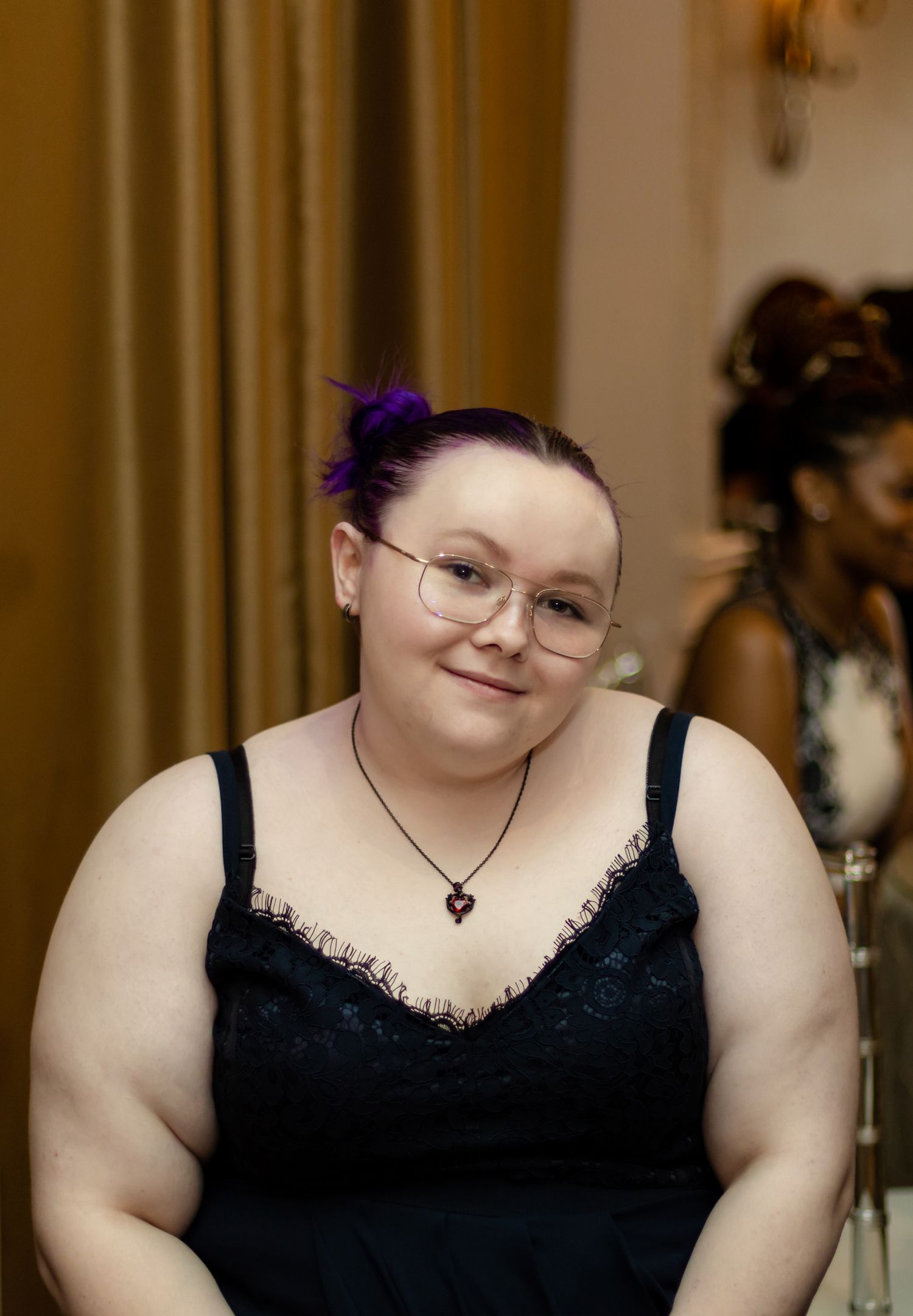 Guest in formal attire seated at an elegantly decorated event venue.