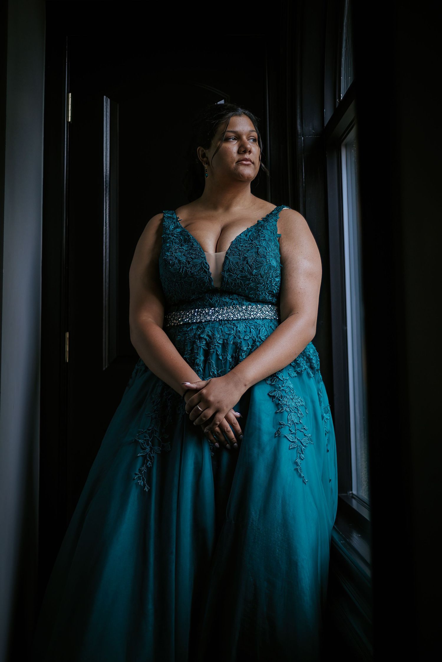 Dramatic portraits in an emerald evening gown against dark window lighting.
