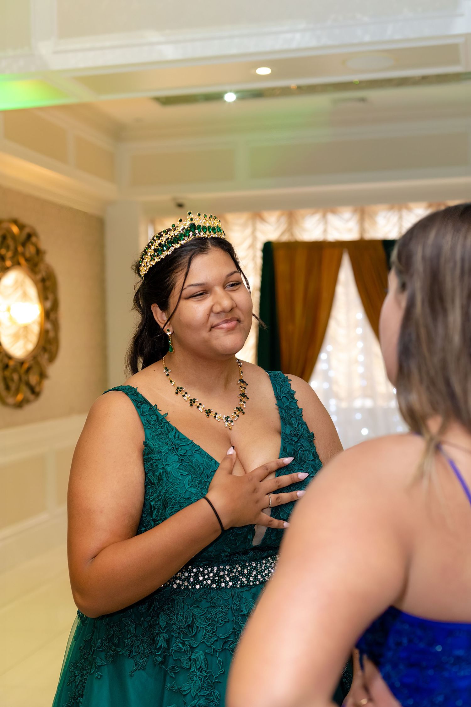 Wedding guests share animated conversations in an elegantly decorated ballroom with green accents.