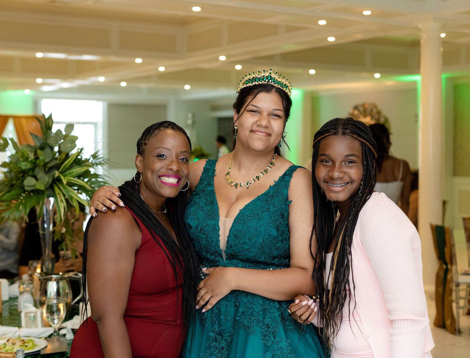 Guests celebrate at a formal event in an elegant ballroom with teal and burgundy attire.