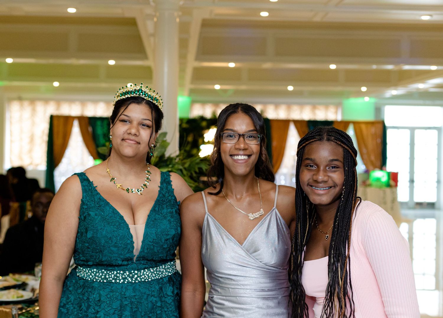 Group photo of attendees in elegant dresses at formal celebration with white columns.