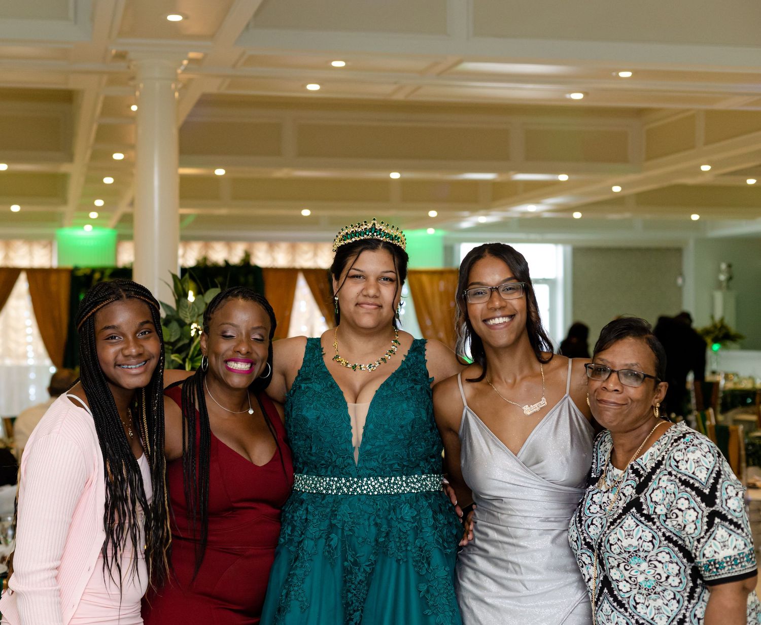 Row of formally dressed guests posing together at celebration with green accent lighting.