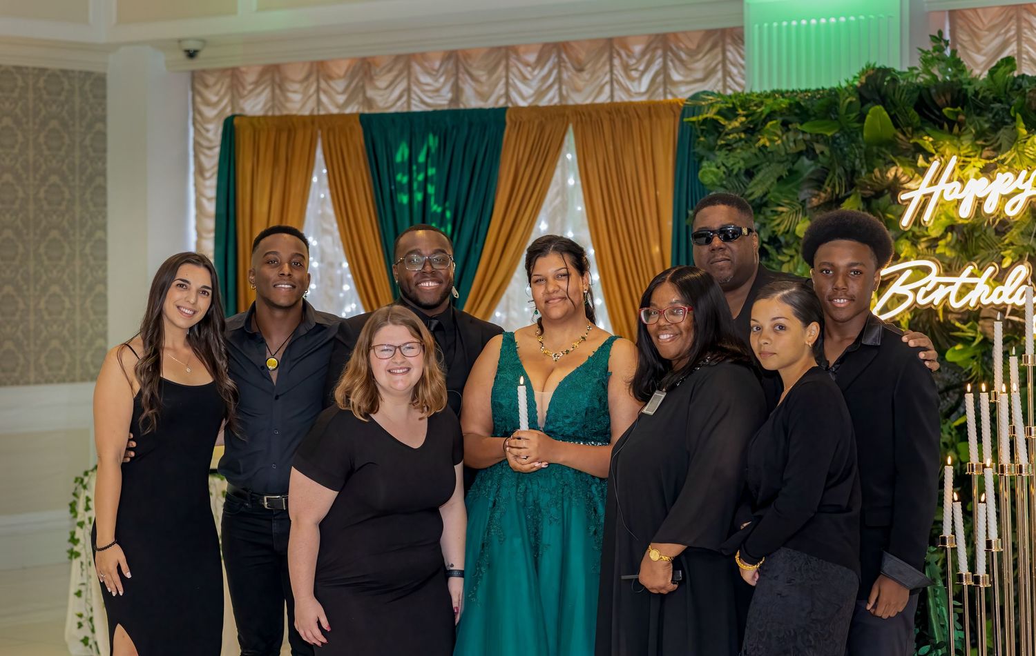 Wedding party members posed together in formal black and emerald green attire.