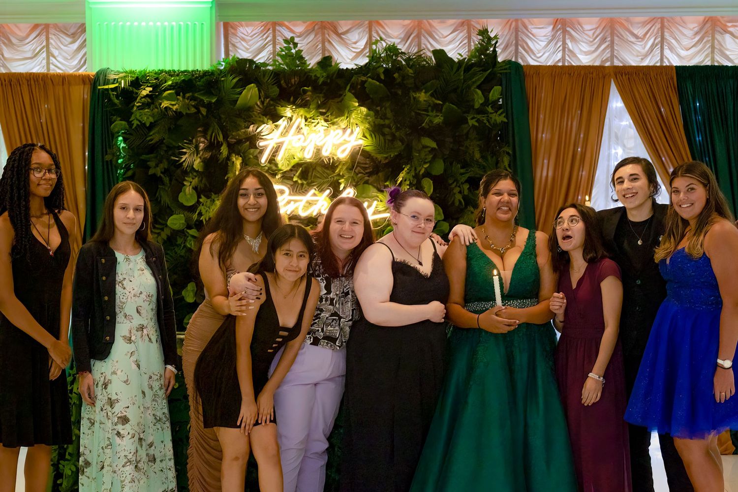 A large group photo of party guests at an elegant venue with draped curtains.