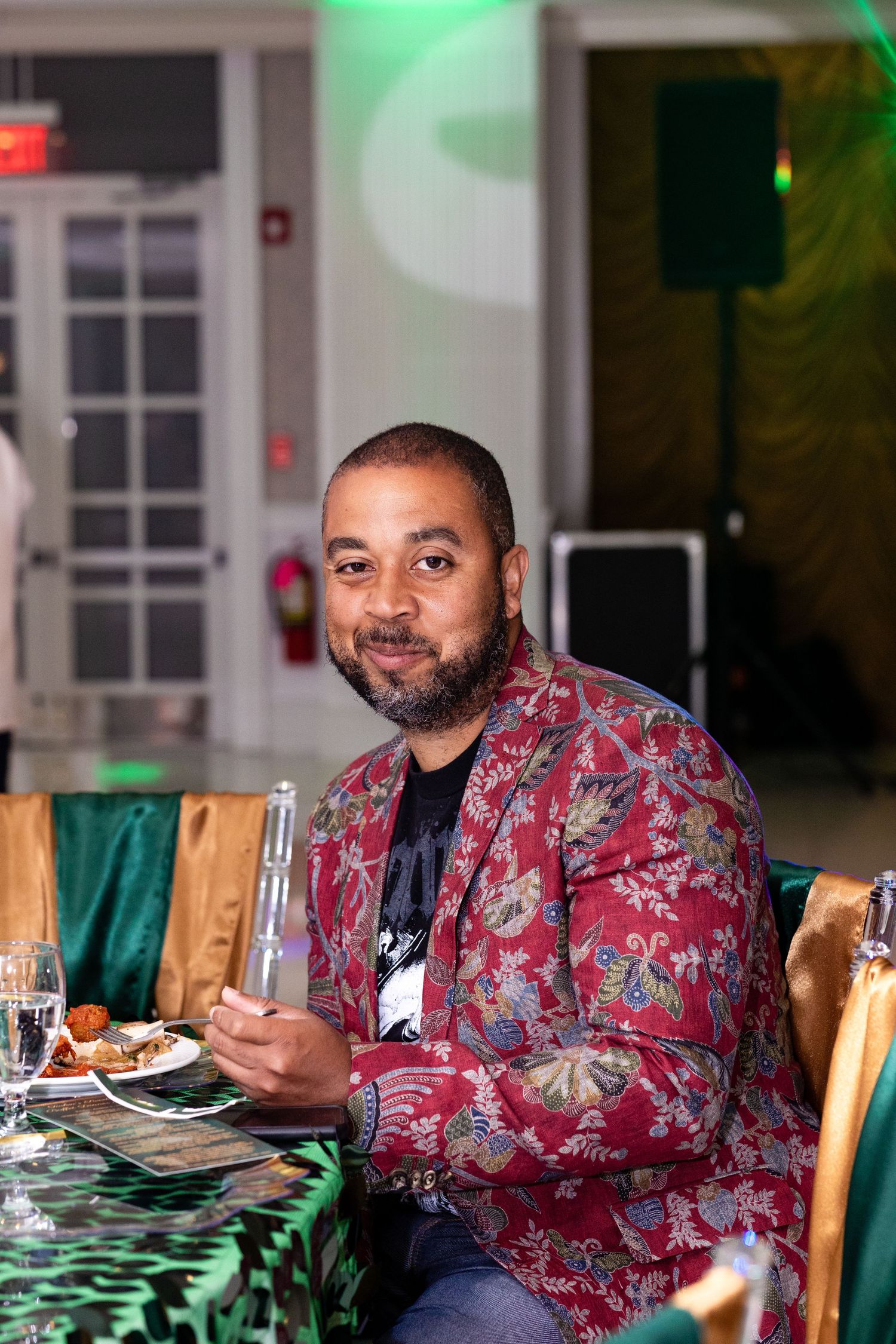Person in patterned red jacket dining at an elegant table setting.