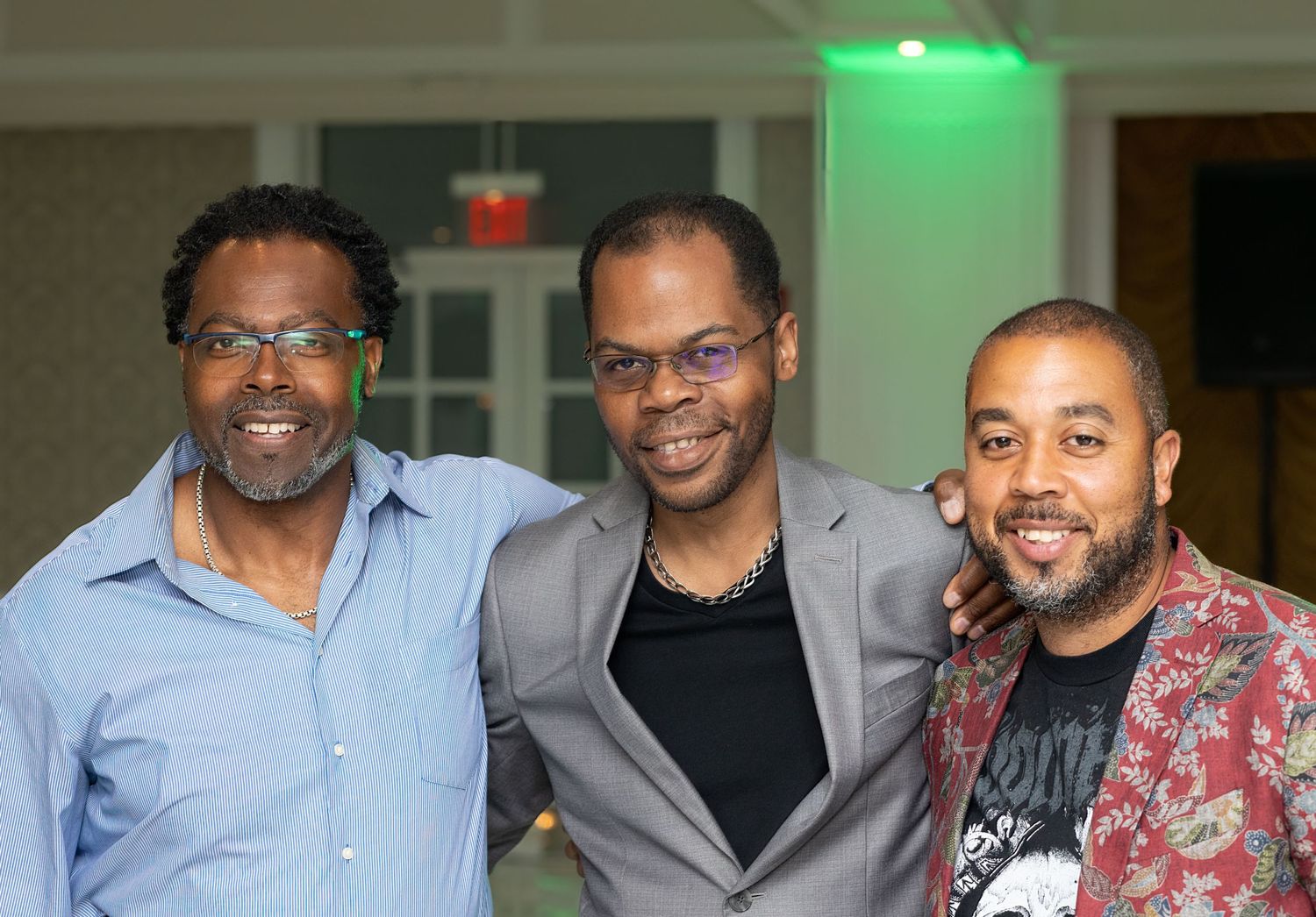 Group photo indoors with people wearing formal attire under green ambient lighting.