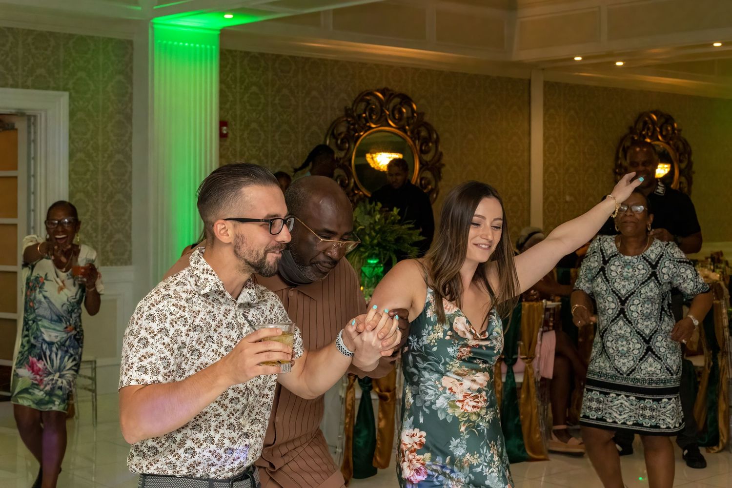 Celebratory gathering in an ornate ballroom with green ambient lighting.
