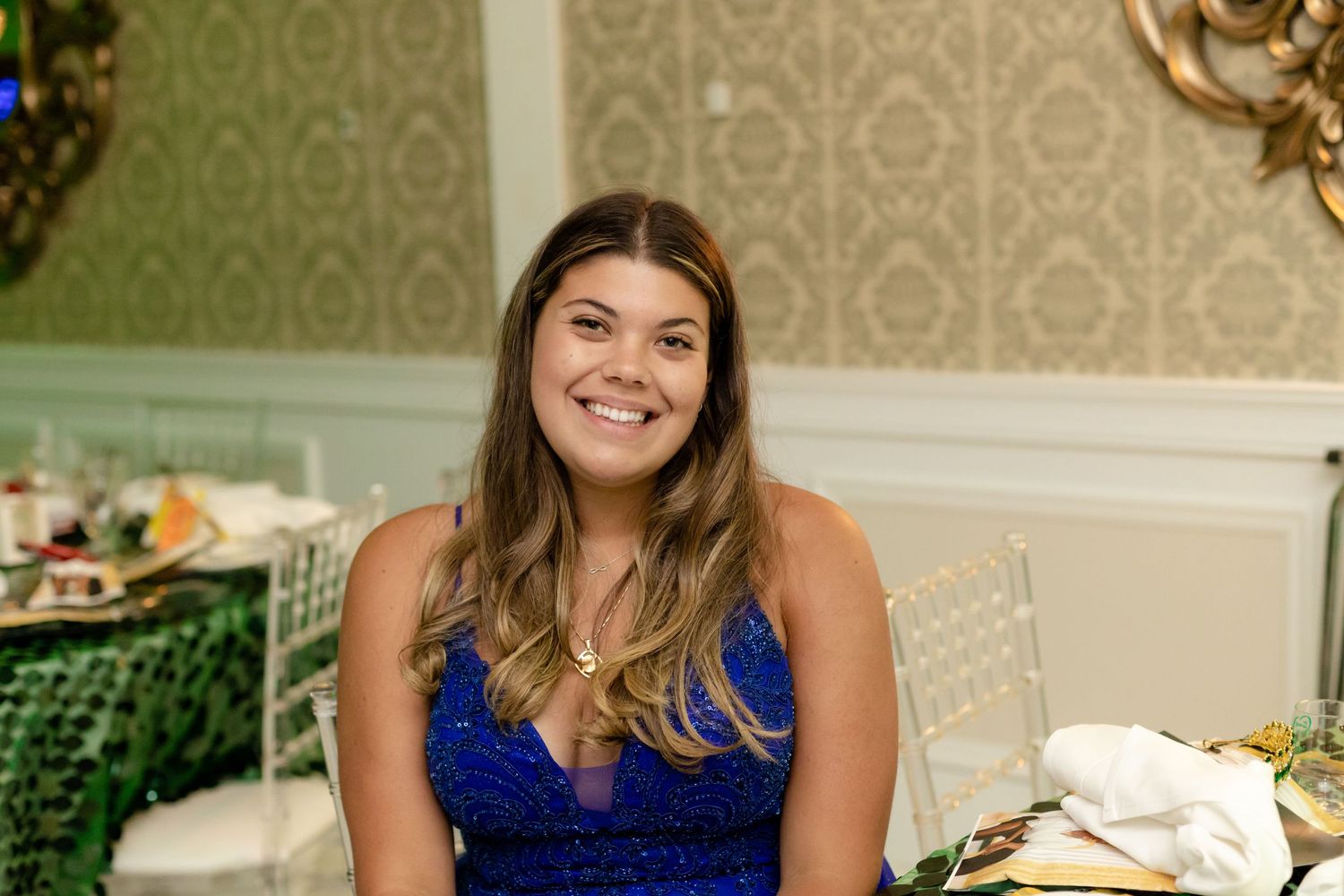 Guests mingle and celebrate at an elegant indoor reception with gold decor and green lighting accents.